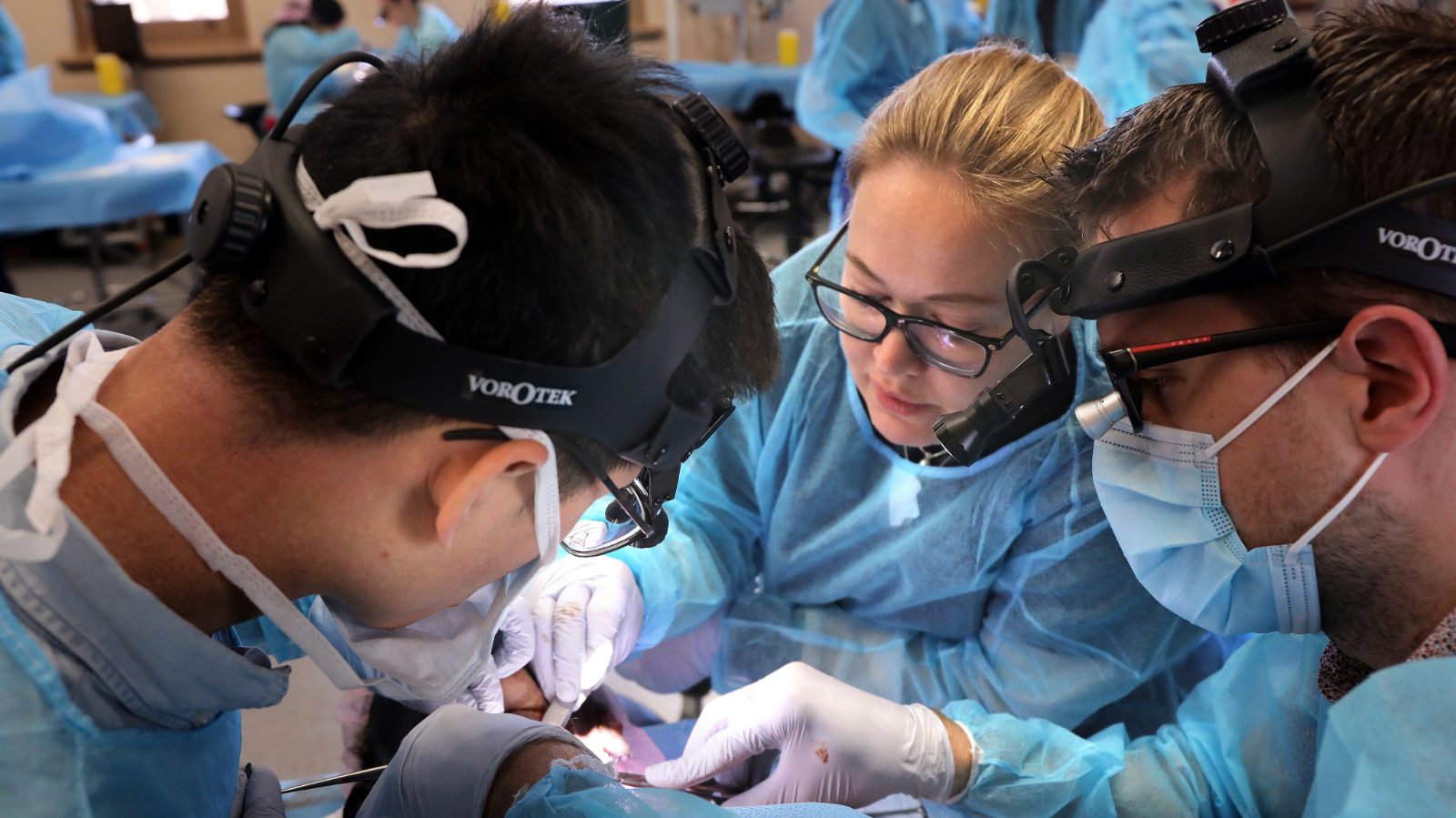 Practitioners in surgical loupes and headlamps working together during a cadaver course